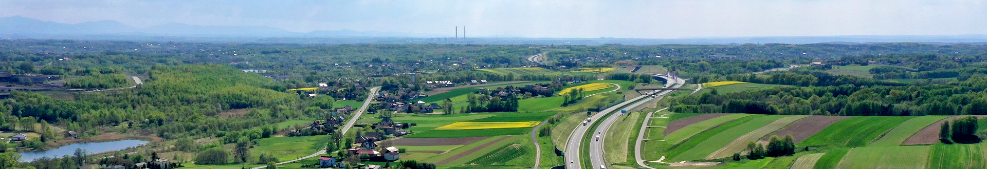 Widok z lotu ptaka na Gminę Mszana, z lewej droga wojew&oacute;dzka ulica Wolności, z prawej autostrada A1, w środku zielone pola, drzewa i zabudowania mieszkalne