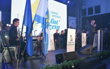 Na scenie Zastępca Gminy Mszana, pan Błażej Tatarczyk przedstawia informacje dotyczące Rozrywkowej Orkiestry Gminy Mszana